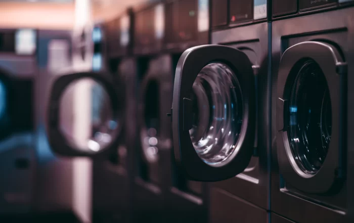Row of commercial front-loading washing machines in a laundromat, with several machine doors open and ready for use.